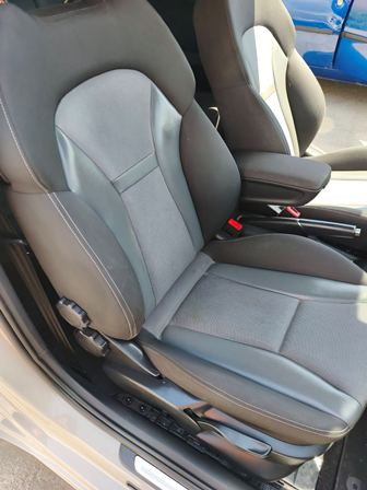 Two gray fabric front seats with black side panels and a center console between them in a car interior. Whether driver and passenger seats are visible.