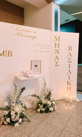 Guest message station with white floral arrangements, framed card, and candles under 'Leave a Message' at a bright event space.