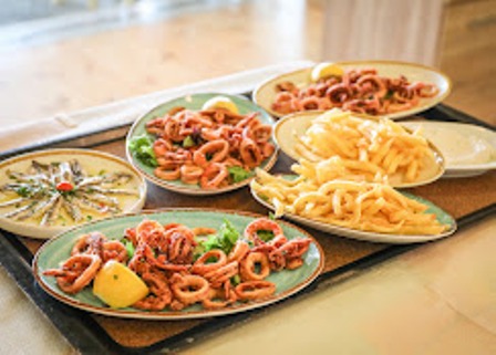 Assorted fried seafood and sides on blue plates arranged on a tray, with lemon wedges on the side.