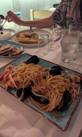 Seafood linguine with mussels on a blue rectangular plate at a restaurant table.