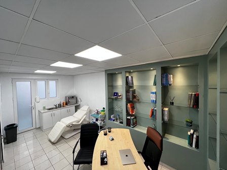 Treatment room with a beige recliner, a wooden desk and chairs, and green built-in bookshelves filled with books.