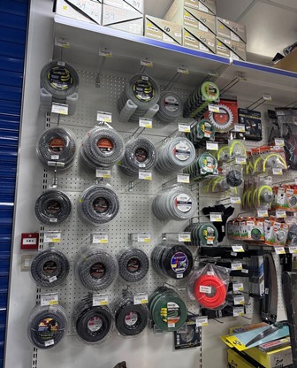 Row of coil tapes on a pegboard display in a hardware store, showing assorted electrical and masking tapes with price tags.