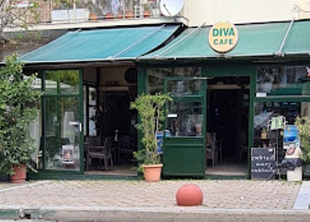 Front view of Diva Cafe with green awnings, glass doors, and potted plants along the entrance.