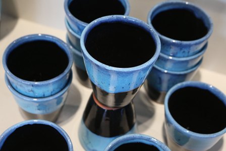 Cluster of empty blue glazed ceramic cups arranged on a surface, viewed from above.