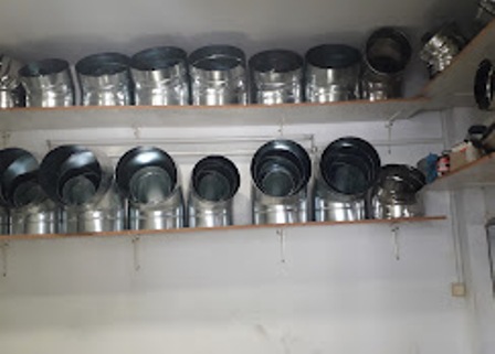 Shelf-filled workshop with metal duct elbows and short connectors arranged on two wooden shelves.]?