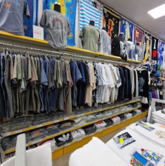 Clothing store with two long racks of folded shirts and hanging tees, and jerseys on the back wall