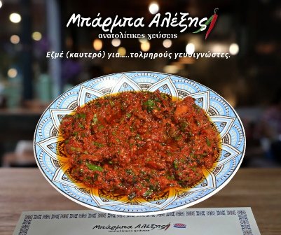 Plate of tomato-based meat dish garnished with parsley on a decorative blue-and-white plate at a Greek restaurant.
