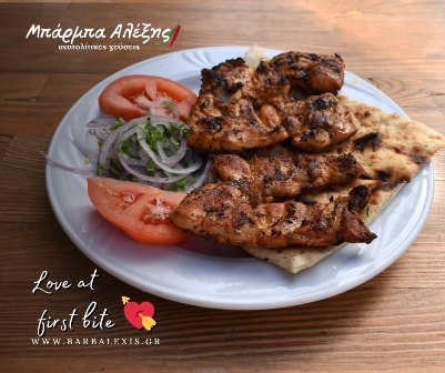 Plate of grilled chicken skewers with tomato slices and onion on a white plate, resting on a wooden table; 'Love at first bite' watermark in corner.