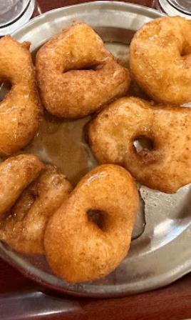 Golden-brown medu vada doughnuts on a metal plate, a popular South Indian snack.